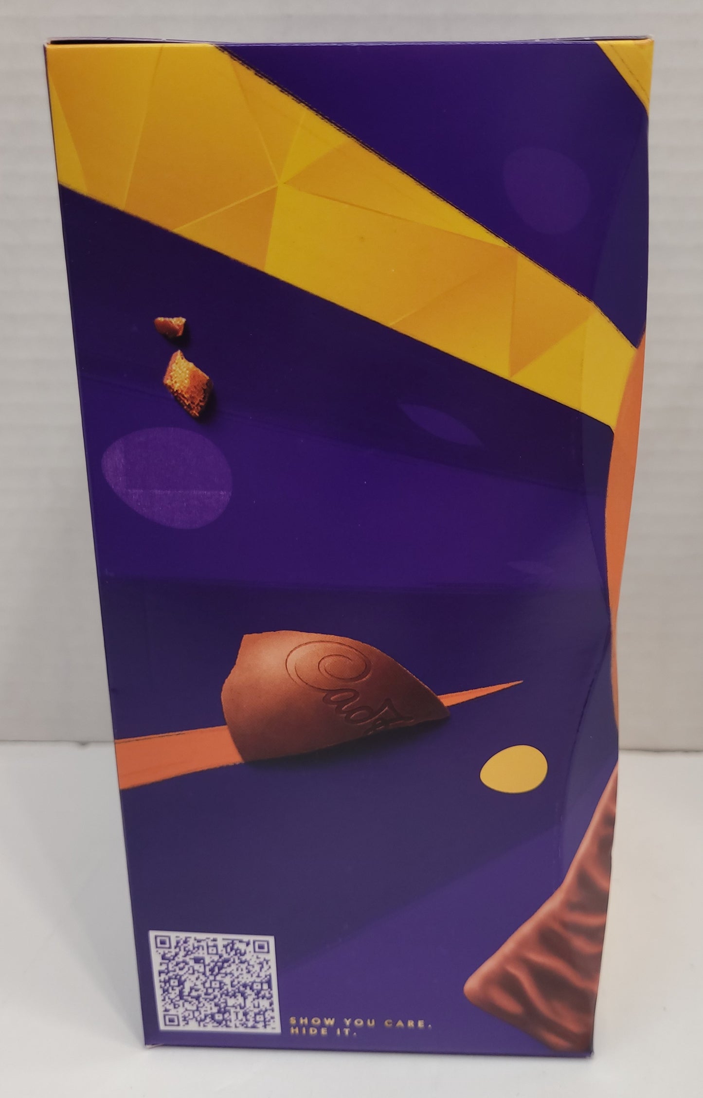Side view of box - A hollow chocolate egg made with the world-famous Cadbury Dairy Milk chocolate and filled with two Cadbury Crunchie bars. Bright festive packaging perfect for the holiday! Contents: One hollow chocolate egg and two bars of honeycombed milk chocolate. Size: 190g. Imported from the UK