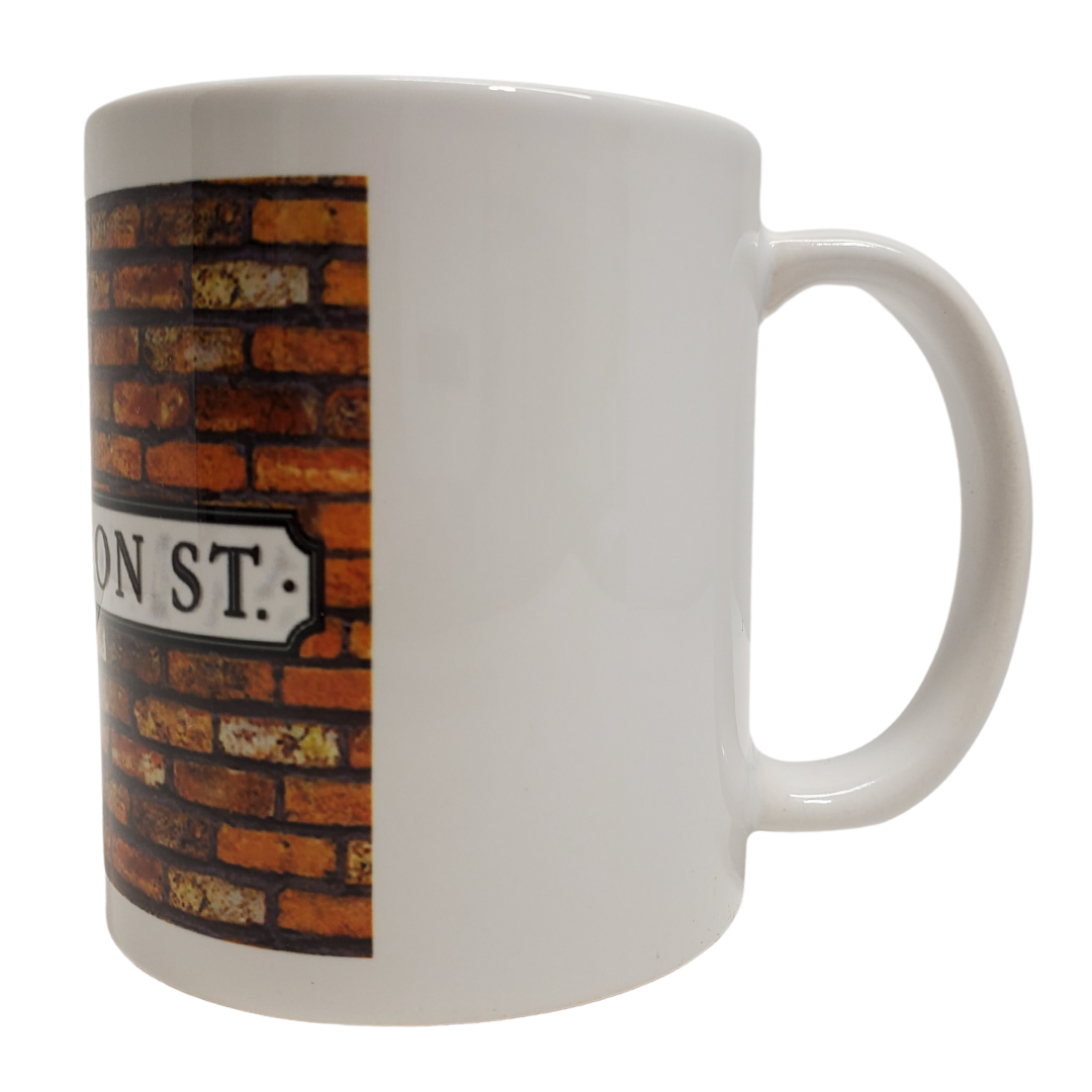 Enjoy your morning brew in our Coronation Street-themed coffee mug. This is the perfect gift for the Coronation Street lover in your life! Features the text "CORONATION ST" on a brick background on a white mug. Standard-sized coffee mug.  You can get a matching magnet for only $2.99 with the purchase of a mug! 