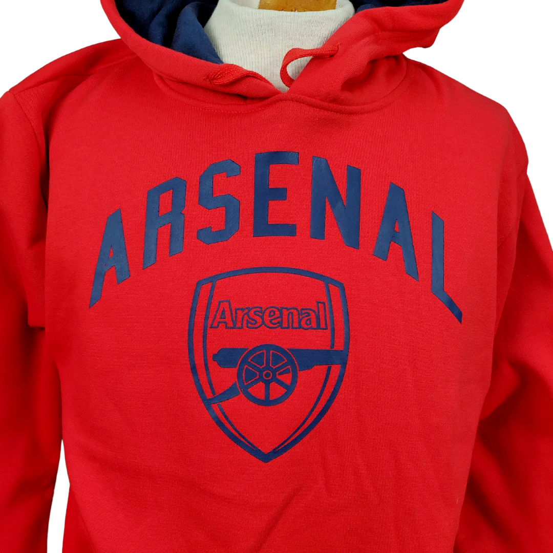 Close up view of Arsenal logo - Bright red Arsenal football club hoodie. The Text "ARSENAL" is in navy blue in big bold letters across the chest. Below the text is the teams official crest in navy blue