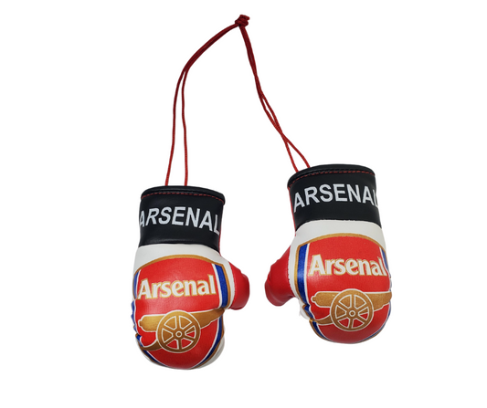 Set of mini Arsenal boxing gloves. Tied together with a red string. The red gloves have the official Arsenal crest with a gold cannon. Around the wrist of the gloves is a black band with white text reading "Arsenal." 