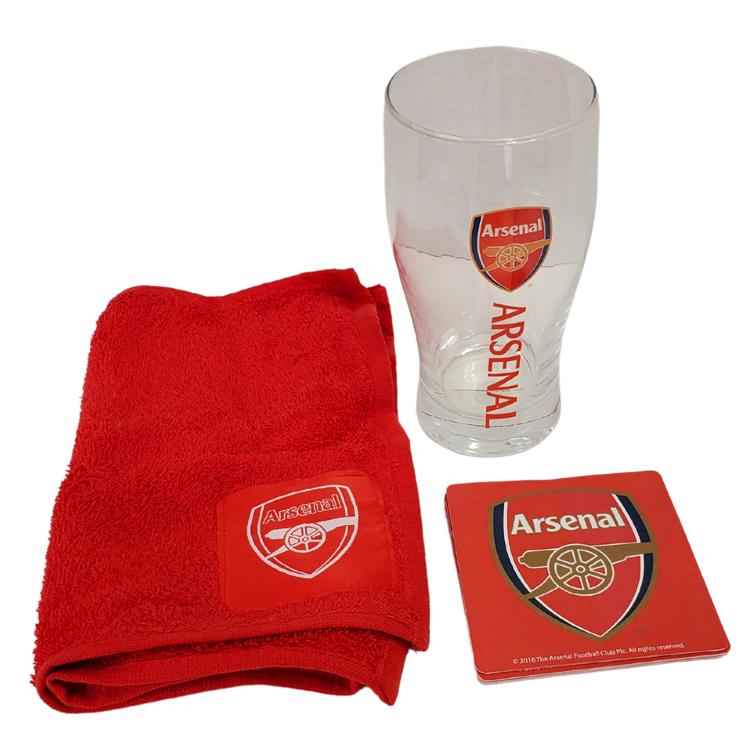 Official Arsenal at home bar kit. The photo contains a red Arsenal cloth with the official crest in the lower corner. Also featured in the photo is an official Arsenal tulip pint glass with the official crest and the text "Arsenal." The last item in this photo is a set of four Arsenal coasters with the official Arsenal crest. 