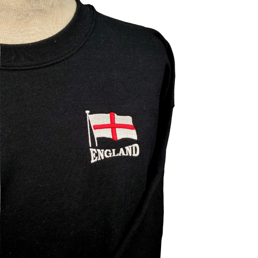 Close up to the Embroidered "England" - Black crewneck sweatshirt with the England flag embroidered on the left breast with the text "ENGLAND" embroidered in white