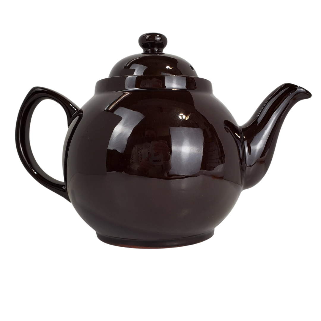 During the reign of Queen Victoria, tea was a symbol of one of the greatest periods in Britain's history. Everyone owned a teapot in this era, many owning the "Brown Betty". Tea was no longer something the upper class could enjoy but became a household staple. This Brown Betty teapot is made from red terracotta and Rockingham glaze. Enjoy your perfect cup of tea without the worry of spiling with the specially designed spout. The Union Jack in the photo is a removable stick