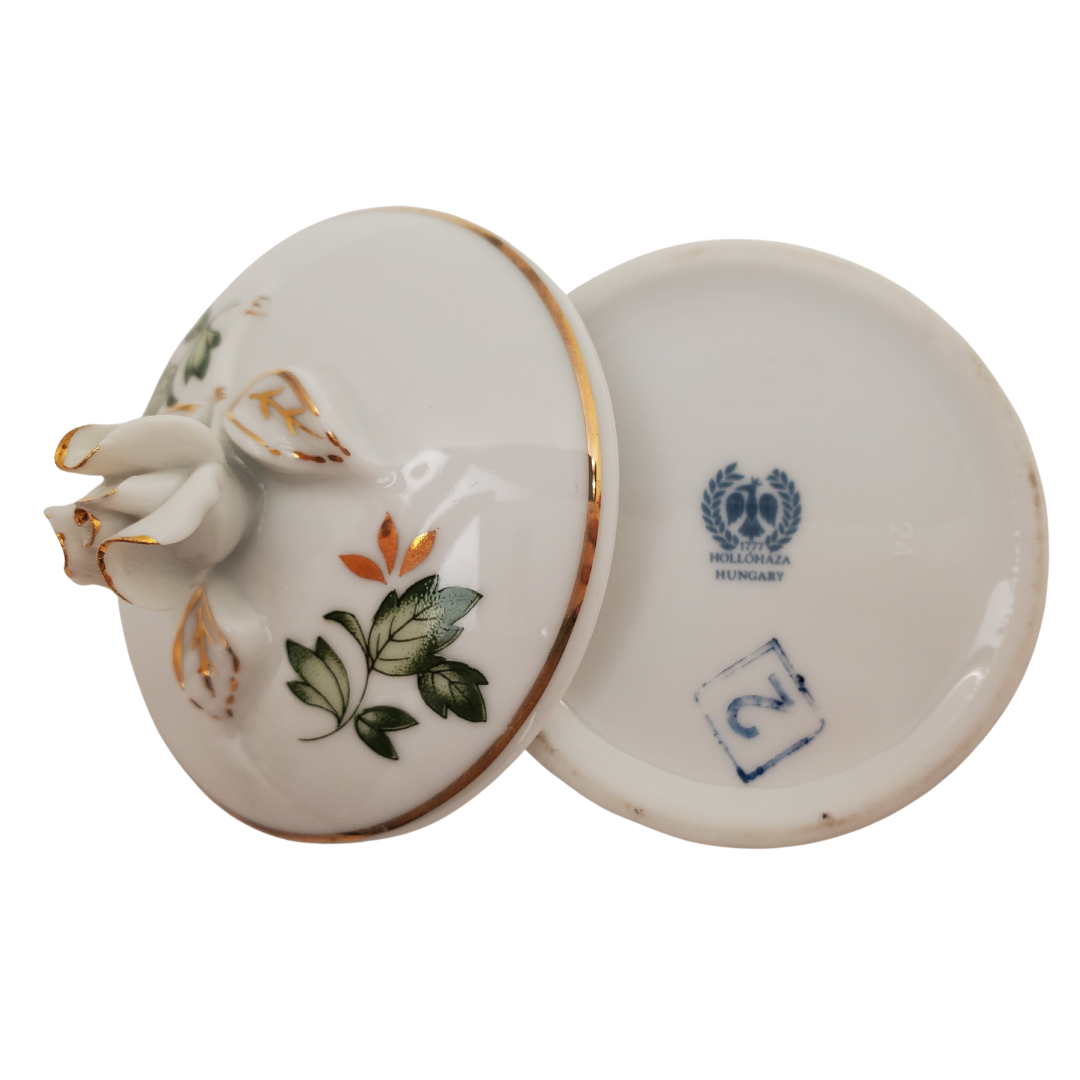 Bottom View - Pre-owned Hollohaza Hungary porcelain trinket box, with green leaves, gold leaves, gold trimming, and rosebud as handle. Perfect addition to your vanity or bathroom for storing cotton pads!  Measurement: Height: 2.5" Diameter: 2/75"