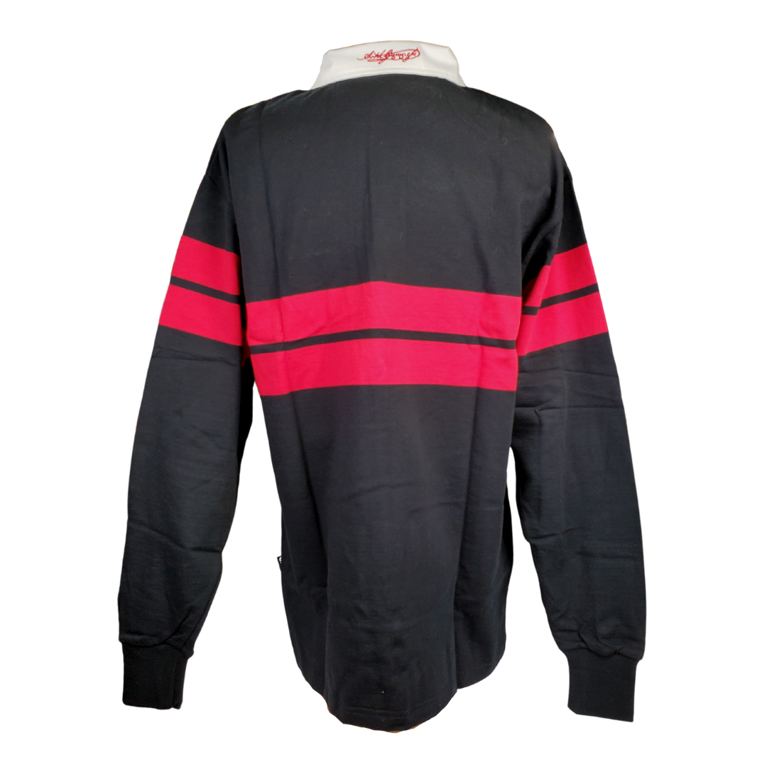 Back veiw - Black long sleeved rugby shirt with a white collar. Two red bads span across the chest and arms. There is an official Guinness patch on the left breast. There is embroidered white text on the right breast.